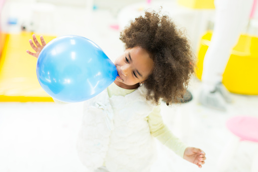 African little girl inflates blue  balloon