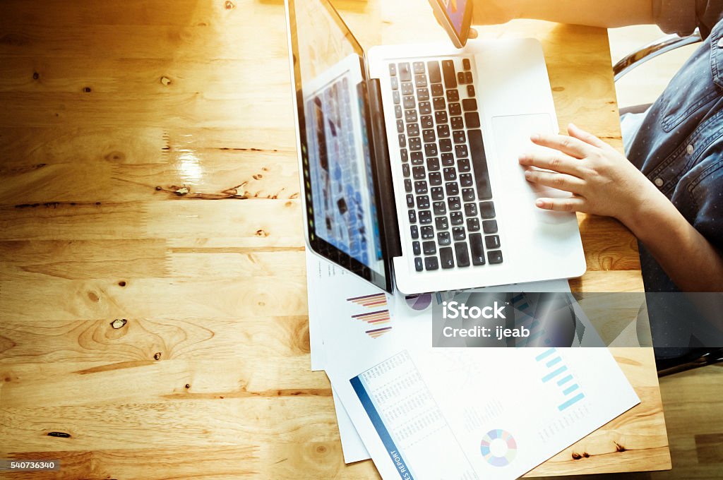 Business woman useing laptop. Startup businessman analyze the marketing charts and graphs on desk. Sunlight filter vintage tone and selective focus. Contemplation Stock Photo