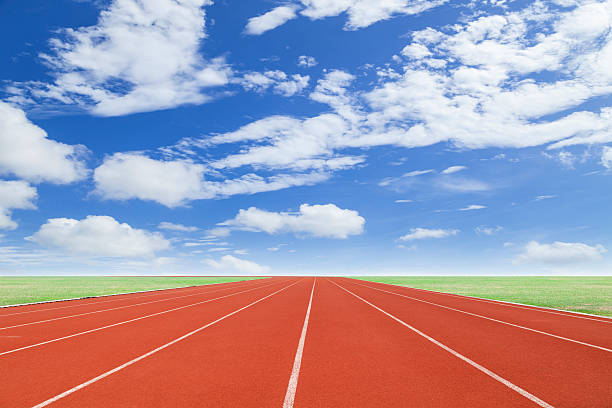 istock Running track with green grass and blue sky white cloud 540737436