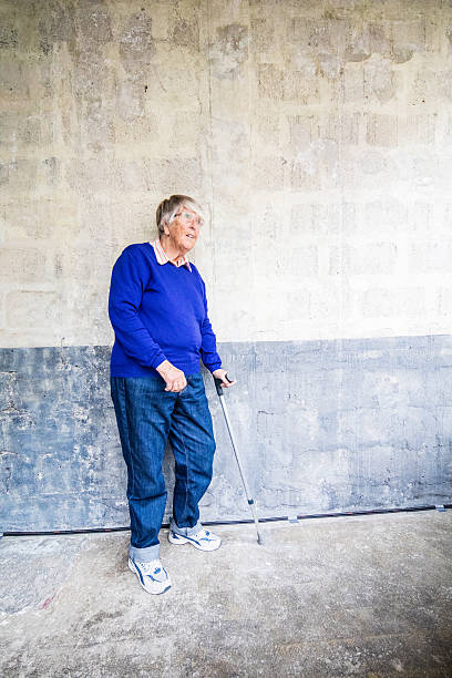 istock Senior woman standing at a wall with crutch 540737712