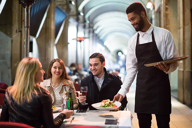 camarero negro que ofrece mesa en la terraza - restaurant waiter table wait staff fotografías e imágenes de stock