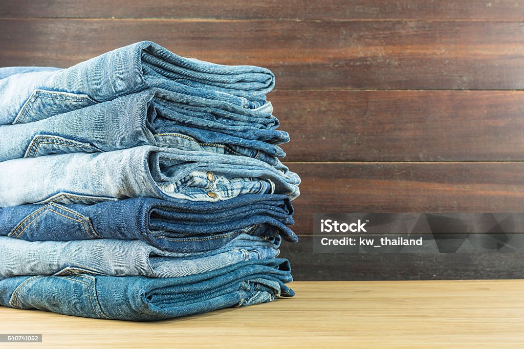 Jeans on a wooden background. Jeans on a wooden background./ Jeans folded stacked layers. Clothing Stock Photo