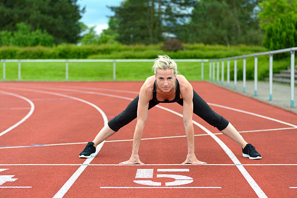 istock Athletic woman doing straddle stretches on track 540742960