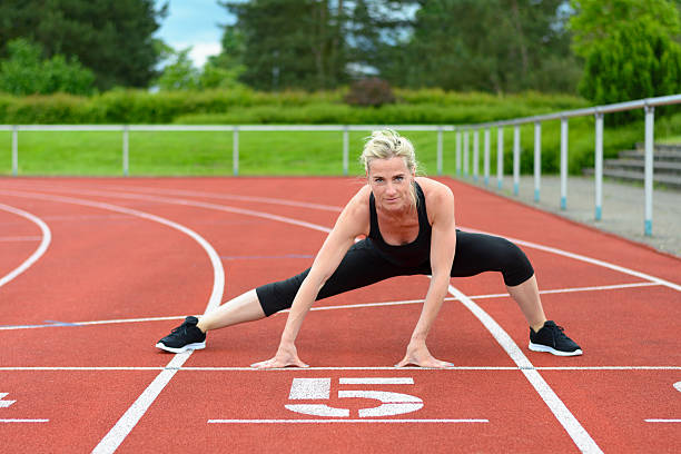 istock Athletic woman doing straddle stretches on track 540743014