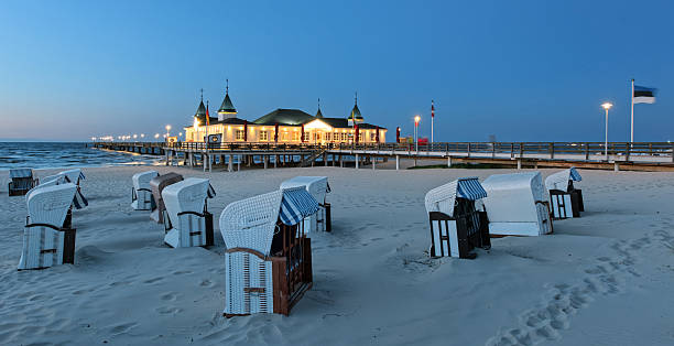 istock Hooded beach chairs and illuminated pier on sand coast 540751372