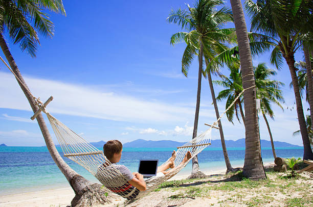 Business man working at laptop in hammock on the beach Business man working at a laptop in hammock on the beach, he is a freelancer. Thailand, Samui. sand river stock pictures, royalty-free photos & images