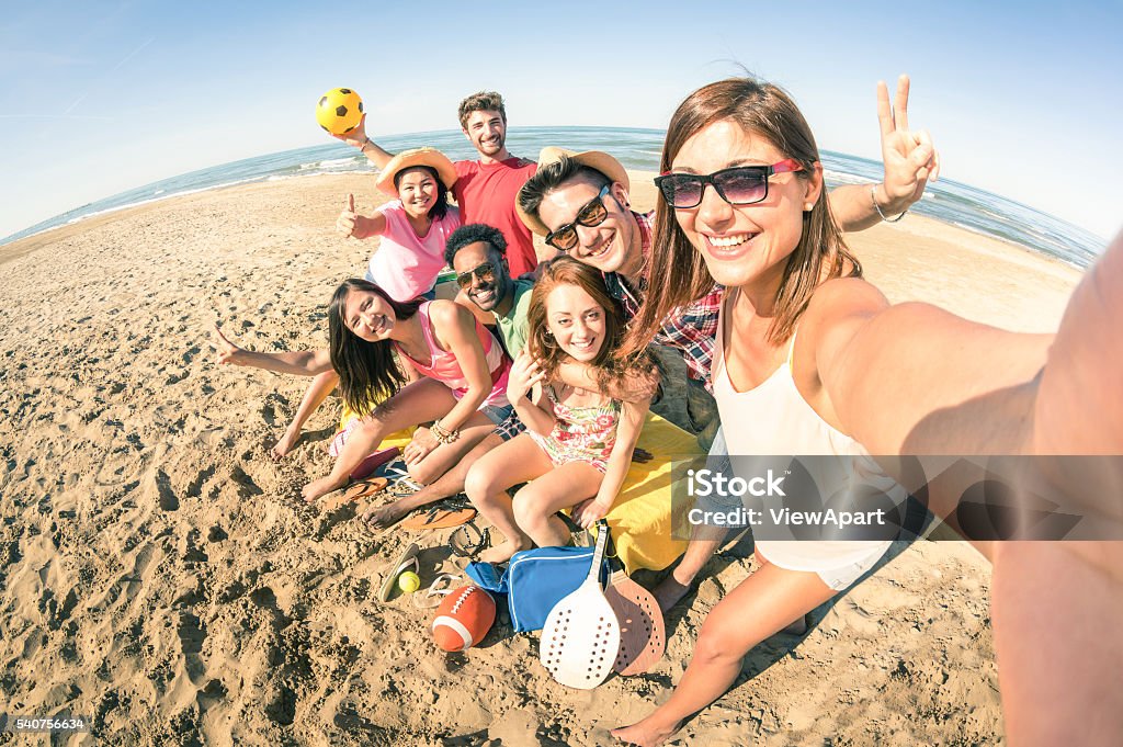 Group of multiracial happy friends taking fun selfie at beach Group of multiracial happy friends taking selfie and having fun with beach sport games - Summer joy concept and multi ethnic friendship - Sunny afternoon color tones with focus on girl holding camera Beach Stock Photo