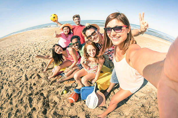 Group of multiracial happy friends taking fun selfie at beach Group of multiracial happy friends taking selfie and having fun with beach sport games - Summer joy concept and multi ethnic friendship - Sunny afternoon color tones with focus on girl holding camera emilia romagna photos stock pictures, royalty-free photos & images