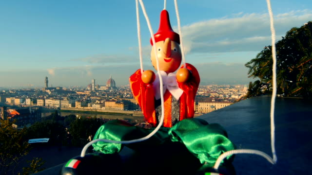Italy Florence puppet Pinocchio sits in front of city landscape