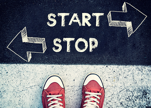 Student standing above the sign for start or stop,dilemma concept