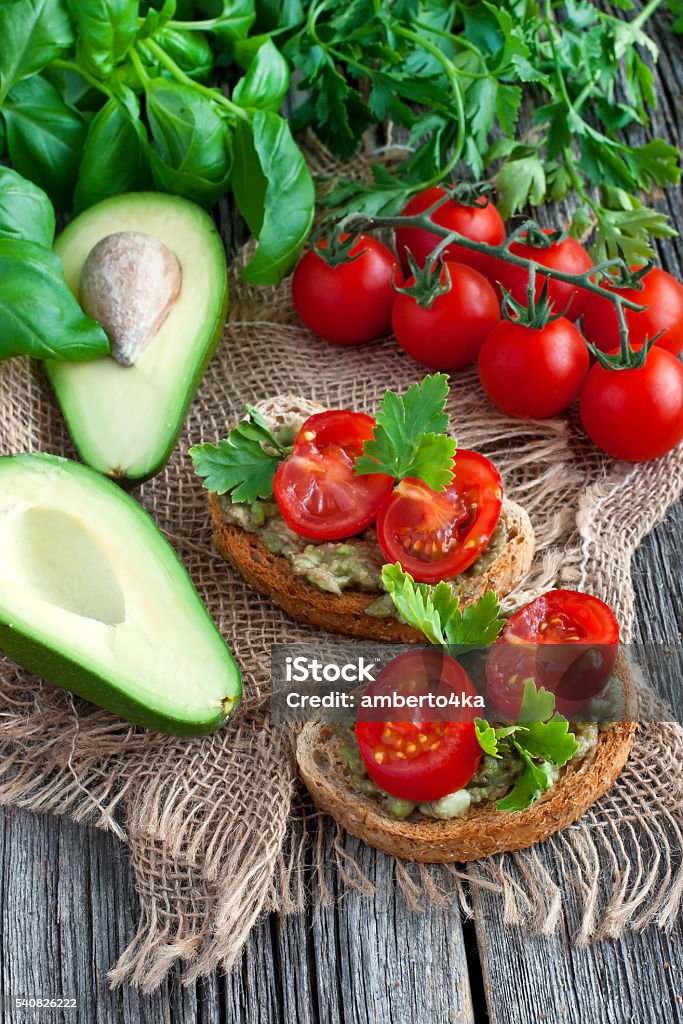 Sandwich with avocado and tomato on  wooden board Vegan sandwich with avocado and vegetables on wooden background Avocado Stock Photo