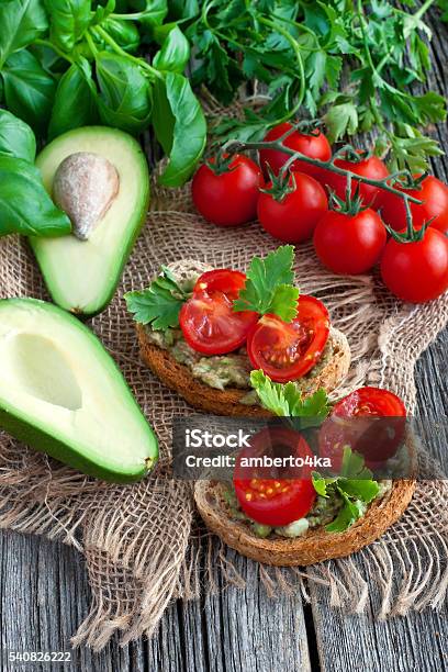 Sandwich With Avocado And Tomato On Wooden Board Stock Photo - Download Image Now - Avocado, Basil, Bread
