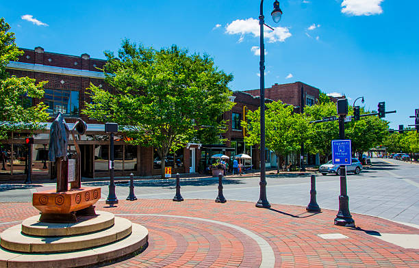 Roundabout in Durham, North Carolina Durham, USA - June 18, 2016: A statue on a roundabout in the centre of Durham, North Carolina, USA. Various people at a cafe in the distance, various logos. durham north carolina stock pictures, royalty-free photos & images