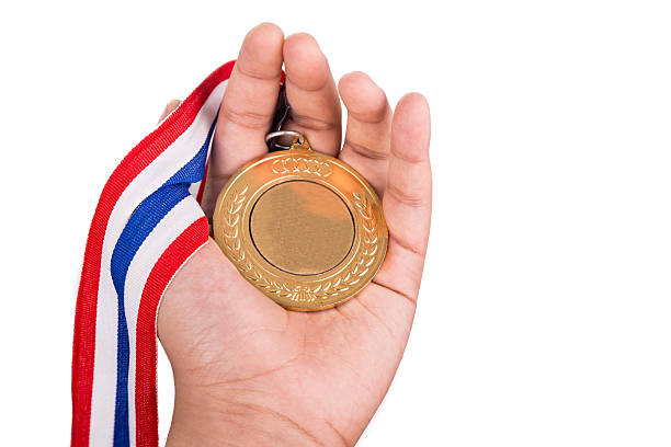 istock Athlete holding gold medal with ribbon on his hand 540836886