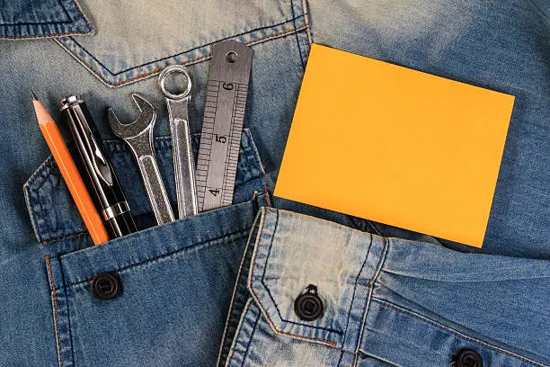 Photo of Jeans with wrench tools and paper note on a denim.