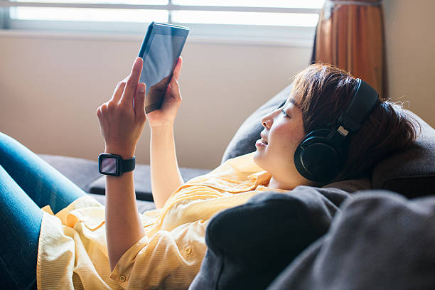 デジタルタブレットを使用して若い女性 - リスニング ストックフォトと画像