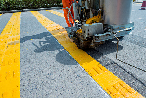 Pavement marker machine spraying yellow lines at a urban road.