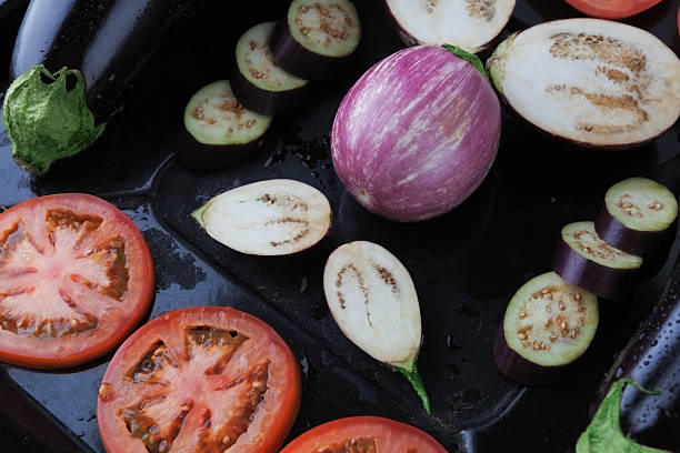istock Whole and sliced eggplants and tomatoes on baking tray closeup 540844322