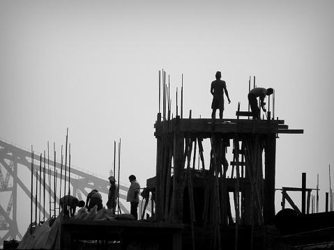 Kolkata, India - May 15, 2016: Construction workers and Engineers working for the construction of a high rise building in Kolkata with the famous Howrah Bridge in the background