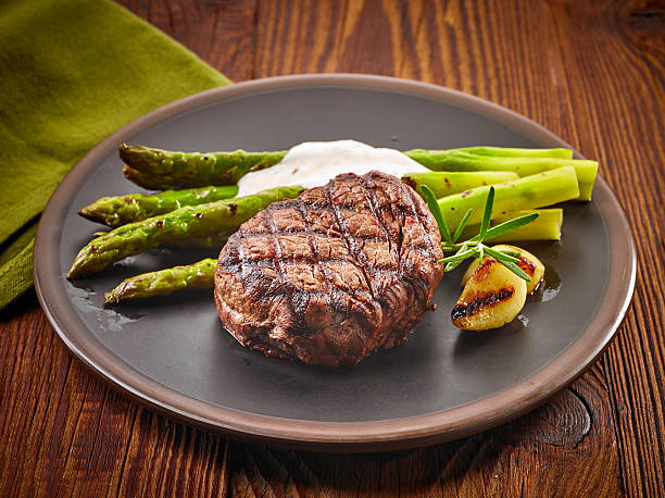 grilled beef steak and asparagus on dark plate