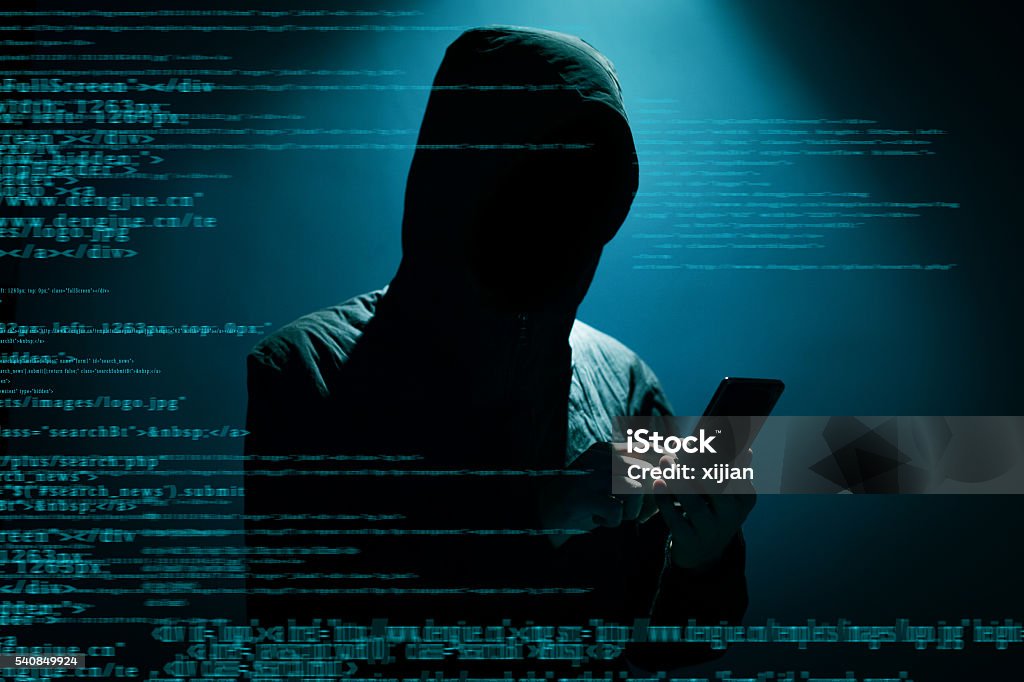 Hacker using phone Hacker Hacker using phone at dark Computer Hacker Stock Photo