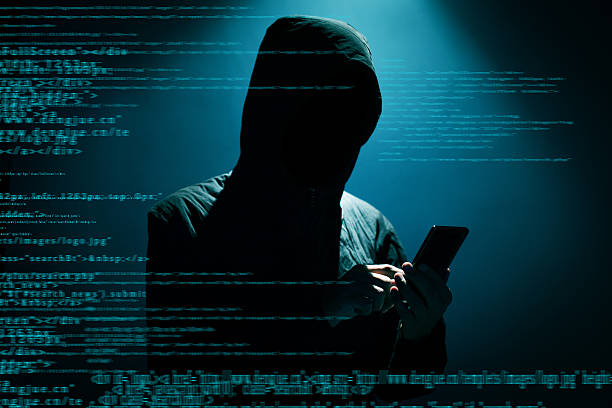 Hacker using phone Hacker Hacker using phone at dark spy stock pictures, royalty-free photos & images