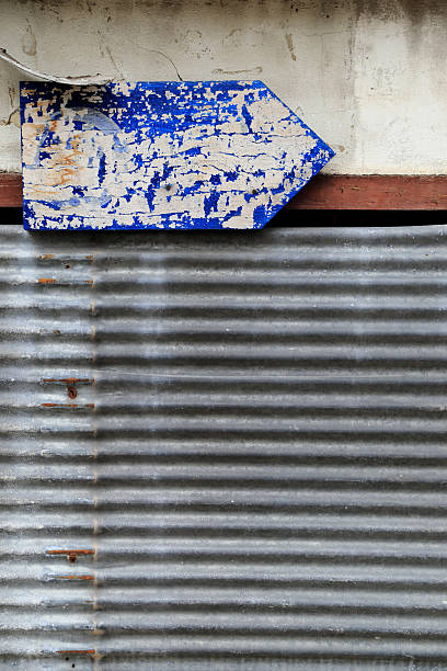 zardzewiałe żelazko faliste i brudna ściana z grungy niebieską strzałką - sign rust old fashioned corrugated iron zdjęcia i obrazy z banku zdjęć