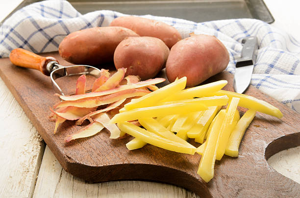 papas fritas recién cortadas sobre una tabla de madera - french fries fast food french fries raw raw potato fotografías e imágenes de stock