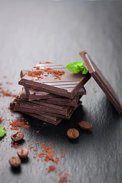 Photo of Stack of chocolate chunks on a dark stone background