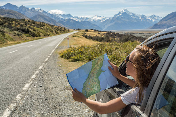 Checking the right way Portrait of a young woman in a car looking at a map for directions. mt cook photos stock pictures, royalty-free photos & images