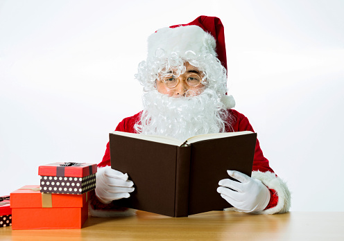 Santa claus reading a book isolated on white background.