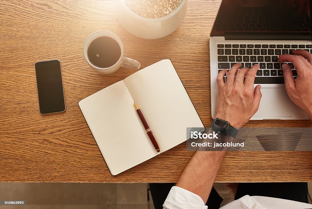 Businessman working at his desk Top view of businessman working at his desk. Modern workplace with laptop, smartphone, diary and coffee cup. Desk Stock Photo