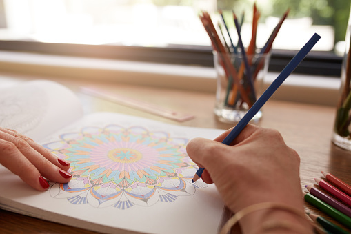 Human hands drawing in adult coloring book