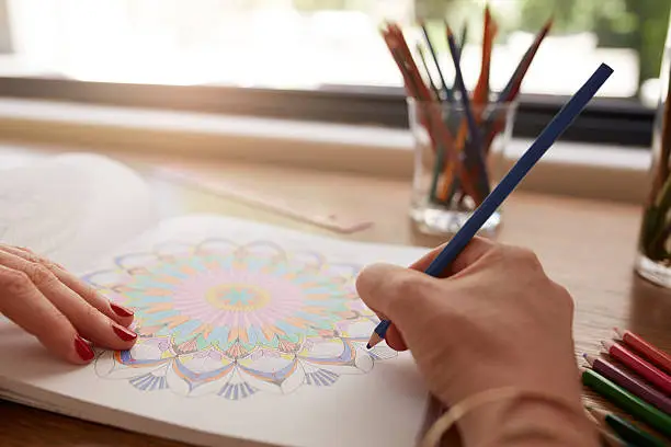 Photo of Human hands drawing in adult coloring book