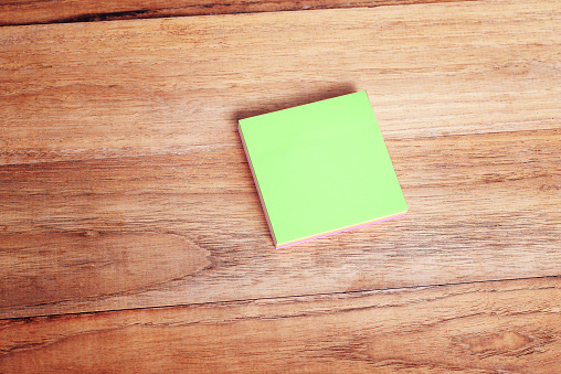 Stack of blank sticky note pad on wood table.