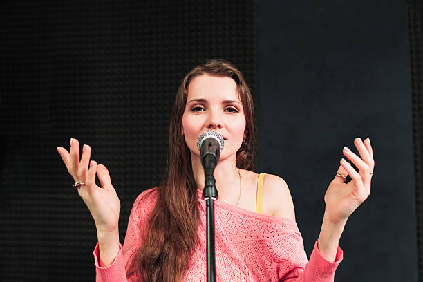 istock Young singing woman inro the microphone close-up 540869578