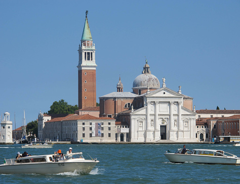 Venice, Italy - July 2, 2015: A pair of motoscafi cross paths in front of Il Redentore on the island of Giudecca.