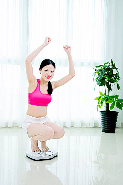 istock Happy woman on weighing scale 540965064