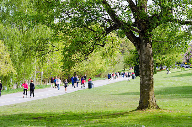 Seattle, United States - April 29, 2012: People walk, run, jog and bike along a paved path at Green Lake Park in Seattle. The park opened in 1903 and was designed by John Charles Olmsted and Frederick Law Olmsted, Jr.