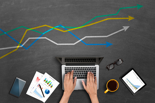 High angle view of a cropped image of businessman market research global business growth chart on laptop with financial data and statistics.