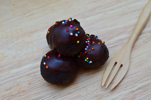 Delicious and soft fresh homemade chocolate ball cake topping with candy sprinkle on wooden board