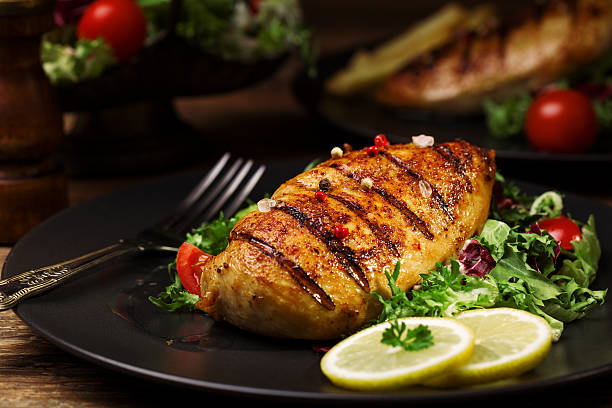 grilled chicken breast with green salad and french fries. grilled chicken breast with green salad and french fries on a black plate. main course stock pictures, royalty-free photos & images