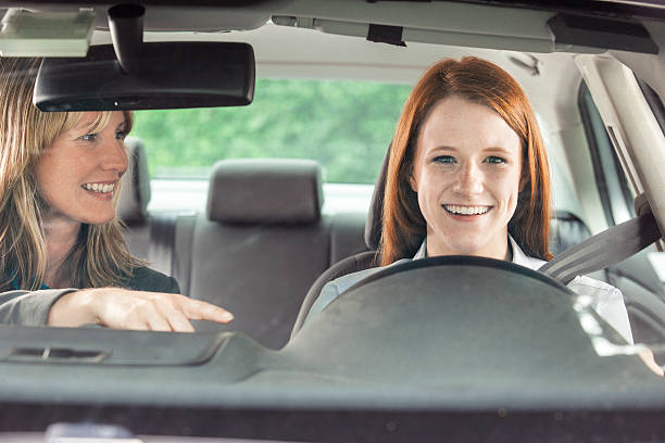 adolescente in auto con istruttore di guida - car insurance women driving foto e immagini stock