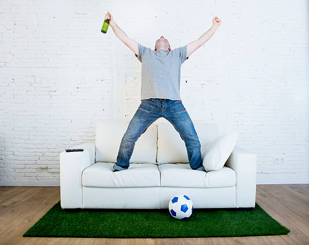 istock fan watching television in couch grass pitch carpet celebrating goal 540971092