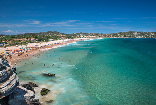 Geribá Beach in Búzios viewed from above. Hot summer day in Rio de Janeiro state with a crowd of people swimming and enjoying the sunshine.