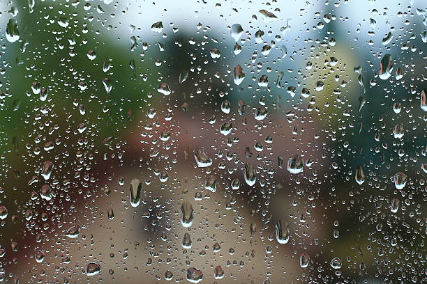 istock Rain drops on window with house and church in background 540974804