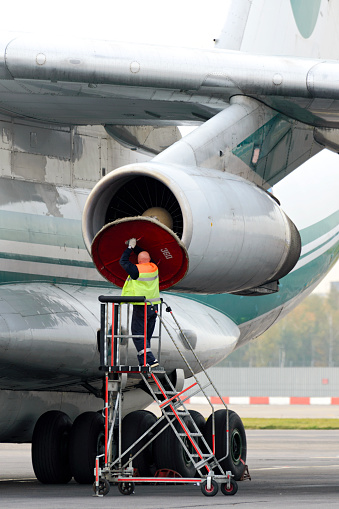 Moscow, Russia - September 26, 2014: Service Engineer serves a jet engine of the plane Il-76TD. Cargo airplane IL-76TD Alrosa airlines parked Domodedovo airport.