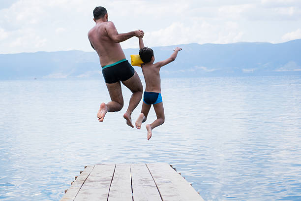 istock Father and son jumping into lake 540976134