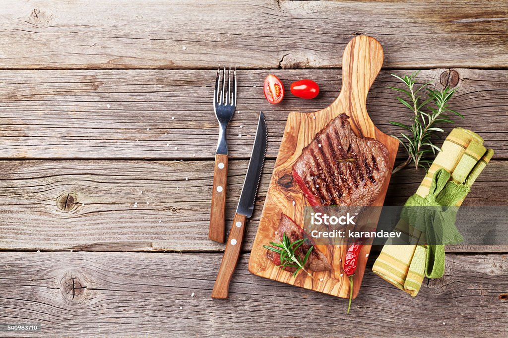 Grilled beef steak Grilled beef steak with rosemary, salt and pepper on wooden table. Top view with copy space Above Stock Photo