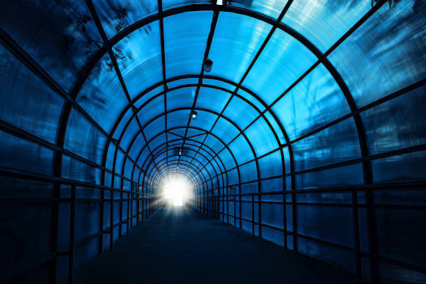 Blue sinister tunnel Dark blue sinister tunnel with shadows on the walls and the light at the end of it light at the end of the tunnel stock pictures, royalty-free photos & images